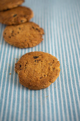 Top view of cookies, the first one focused, on a background of kitchen cloth in vertical