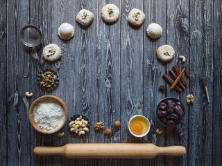 Sweets background. Egg, flour and nuts are laid out on a dark wooden background