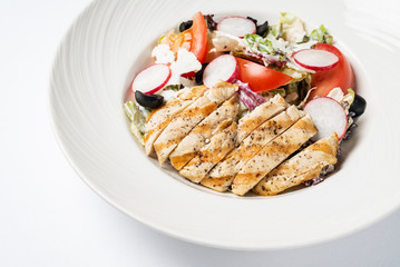 grilled chicken with vegetables on the white plate
