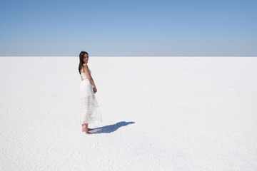 Dark-haired girl in a white dress, salt lake Elton in the Volgograd region in Russia.