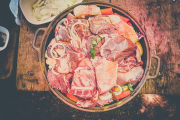 Fresh meat with vegetables prepared for baking, on a wooden table