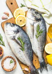 Raw dorado fish on cutting board on the table.