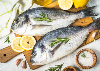 Raw dorado fish on cutting board on the table.