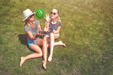 Two girls in sunglasses relax on nature, smile, blow soap bubbles and play watermelon with inflatable ball on a sunny summer day, rest for adults and Ting, outdoors, hard light, shadows, noon