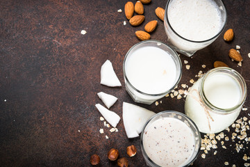 Vegan non dairy alternative milk on dark rusty table.
