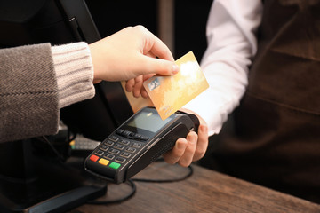 Woman with credit card using payment terminal at shop, closeup
