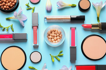 Makeup products and flowers on color background, flat lay