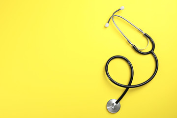 Stethoscope with space for text on color background, top view. Medical tool