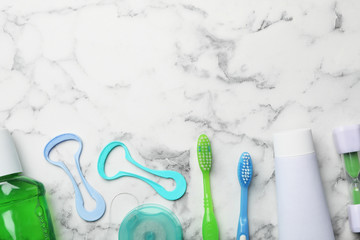 Flat lay composition with tongue cleaners and teeth care products on marble background. Space for text