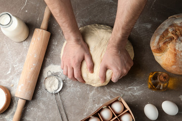 Male baker preparing bread dough at kitchen table, top view