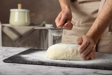 Male baker preparing bread dough at table, closeup