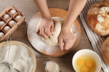 Obraz na płótnie Canvas Female baker preparing bread dough at kitchen table, above view