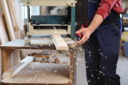 Working man using thickness planer at carpentry shop, closeup