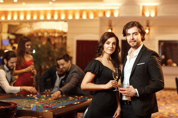 Beautiful glamour couple against the background of casino poker roulette.