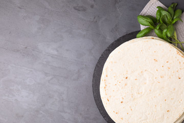 Slate plate with tasty tortillas on grey table, top view. Space for text