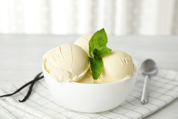 Delicious vanilla ice cream with mint in bowl served on table