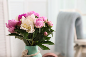 Fototapeta na wymiar Vase with bouquet of beautiful peonies in room. Space for text