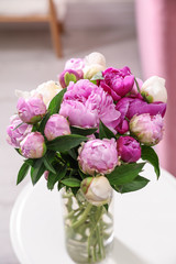 Vase with bouquet of fresh peonies on table in room