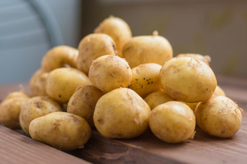 Closeup of a pile of new potatoes on a rustic wooden board.