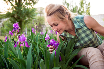 Portrait of a girl in a blooming garden. Woman in summer, gardening, enjoying vacation, morning in the village.  Happy middle-aged woman