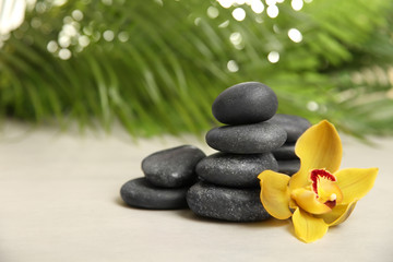 Spa stones with flower on table against blurred background. Space for text