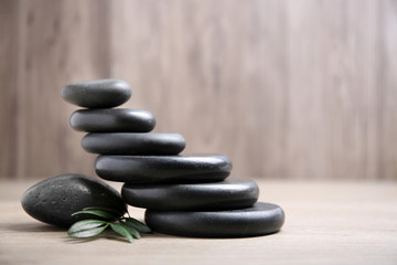 Black spa stones with branch on wooden background. Space for text