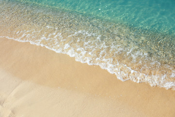 View of sea water and beach sand on sunny day