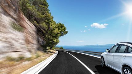 White car rushes along the road to the sea. Motion blur effect.