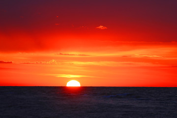 Naklejka na ściany i meble sunrise at the seaside, half the sun comes out of the horizon