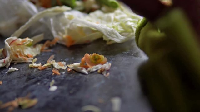 Woman hand clean kitchen from vegetable scraps food waste leftover on kitchen board