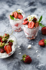Healthy dessert with raw berries. Eton mess with strawberries, cream and meringues in glasses on gray background