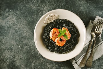 Delicious Italian risotto with grilled big tails of shrimp and cuttlefish ink (squid-ink). Black risotto. Healthy tasty food.  Top view. Copy space. 