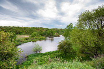 Peaceful landscape with green trees on river bank. Distant view