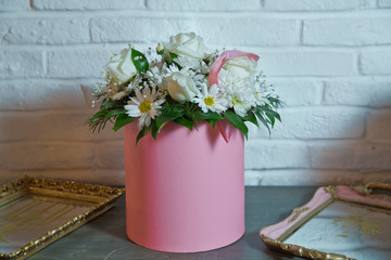 Flower arrangement in a hat box , a pot of pink for a girl on a gift with roses . White and yellow flower pink round bouquet .
