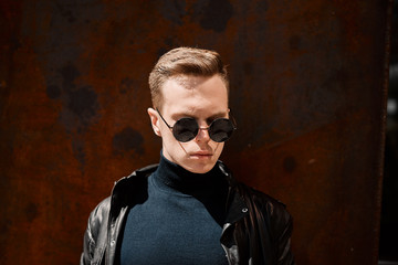 portrait of a handsome young man in sunglasses on a rusty iron background