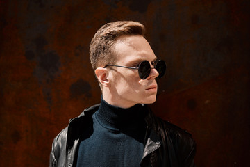 Obraz premium portrait of a handsome young man in sunglasses on a rusty iron background