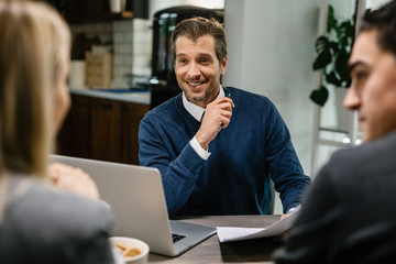 Happy financial advisor talking to a couple on a meeting.