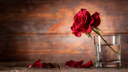 Red rose in vase on old wooden background, Vintage style