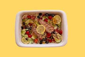 Tasty rice salad with fresh vegetables and grilled mackerel isolated on a bright yellow background