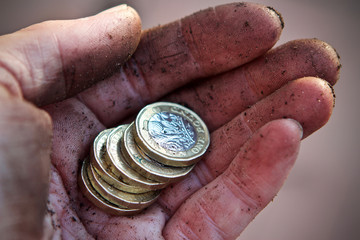 pound coins in palm of a mans dirty hand