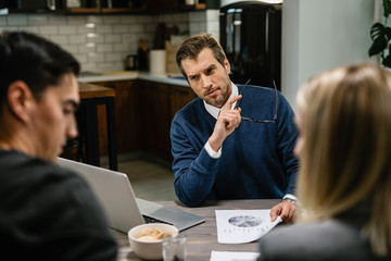 Serious financial advisor discussing about home finances with a couple.