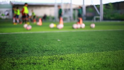 green artificial turf with blurry soccer players are training background.