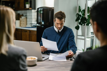 Financial consultant going through paperwork while having a meeting with clients.
