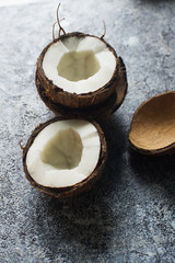 Fototapeta na wymiar Fresh raw organic coconut fruits ripe in halfs over dark stone background