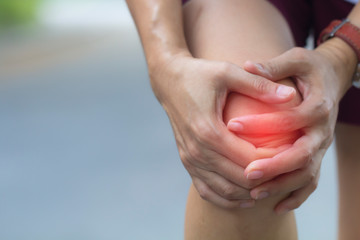 Close up woman knee injury while running on road in the park, Injury from workout concept.