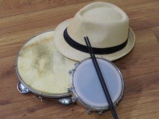 A samba player (sambista) hat and two Brazilian percussion musical instruments: pandeiro (tambourine) and tamborim with drumstick. The instruments are widely used to accompany samba music.