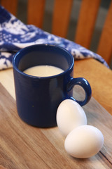 Mug with milk next to an egg 