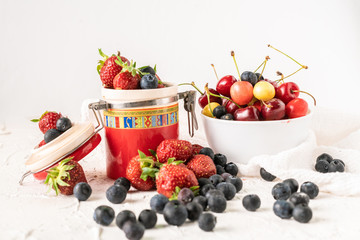 fresh berries of cherry, strawberry and blueberry dropped on the table