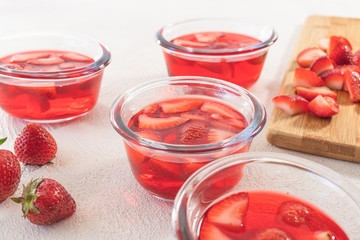 Strawberry Jelly in a Glass Bowls, Sliced Strawberries on a Chopping Board, Close Up, on White Background