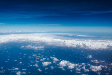Fototapeta na wymiar Plane window view with blue sky and beautiful clouds. As seen through window of an aircraft. View of wing & ocean. Airplane from city Bangkok to island Bali.